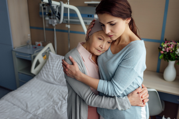 Traurige Tochter umarmt kranke krebskranke Seniorin im Krankenhaus - Foto, Bild