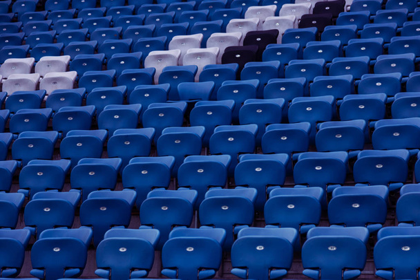 Blank old plastic chairs at the stadium. Number of empty seats in a small old stadium. Scratched worn plastic seats for fans - Photo, Image