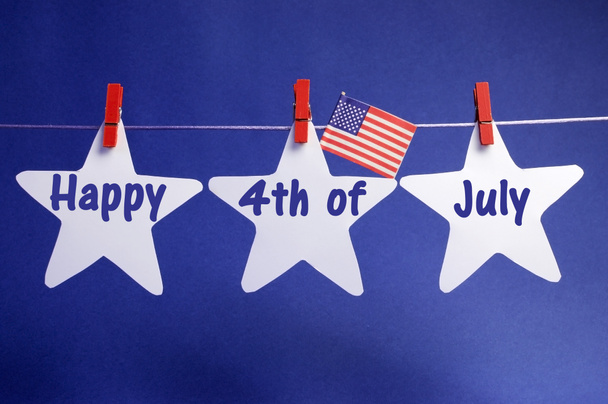 frohe vierte juli botschaft geschrieben über drei 3 weiße sterne mit usa amerikanische fahne hängen an roten stiften auf einer zeile - Foto, Bild