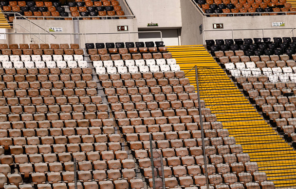 Leere alte Plastikstühle auf den Tribünen des Stadions. Viele leere Zuschauerplätze auf den Rängen. Leere Plastikstühle, Sitze für Fußballfans. Tribüne, Spiel ohne Zuschauer - Foto, Bild