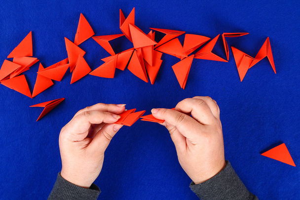 Diy chinese dragon on blue background. Gift ideas, decor Chinese new year. Handmade red gold lunar dragon lion from modular origami. Step by step. The process of crafts. Top view. - Photo, image