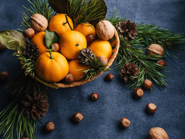 Avellanas, nueces y mandarinas decoradas con ramas de Navidad y conos de pino - Foto, Imagen