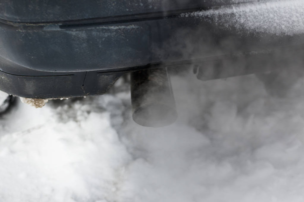 Nieve de invierno. el coche está sucio, el humo viene de su pipa, es real. concepto de contaminación ambiental. hay tonificación
. - Foto, imagen