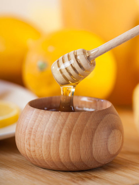 蜂蜜蜂蜜ディッパーとレモンの木のキッチン ボード木製ボウルで. - 写真・画像