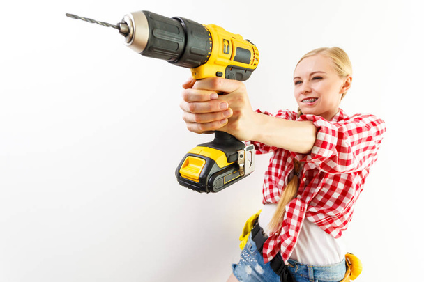 Young determinated woman using drill doing home renovation. Female construction worker having driller tool drilling wall. - Foto, Imagem