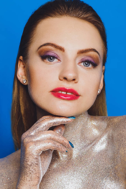 High fashion model girl in colorful bright spangles, glitter, in the studio on a blue background, portrait of a beautiful sexy woman, fashionable glowing makeup. Colorful Brilliant Bright Makeup - Photo, image