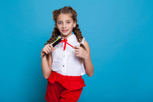 beautiful girl with braids with a red pencil on blue background - Foto, afbeelding