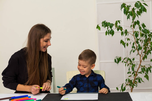 profesora enseña a un niño a dibujar en la mesa
 - Foto, Imagen