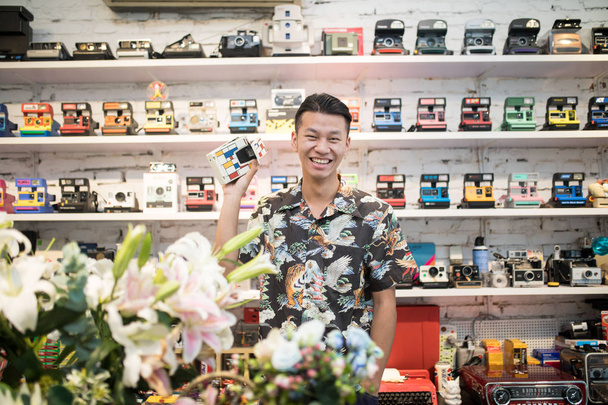 Post-90 chiński człowiek Yu ji, właściciel sklepu pierwszego sklepu kamery Polaroid Hangzhou, pokazuje kamery Polaroid w sklepie w Hangzhou miasta, Wschodnia Chiny prowincji Zhejiang, 30 sierpnia 2018 - Zdjęcie, obraz