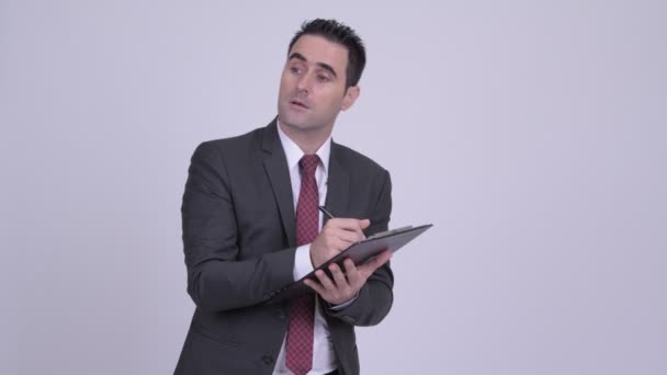 Handsome businessman writing on clipboard - Video