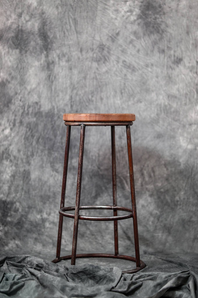 metalen barkruk met een houten stoel op de achtergrond van een grijze stof - Foto, afbeelding
