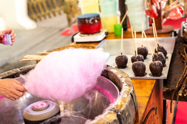 Winkelier een wolk Cotton Candy op een beurs voorbereiden op sommige kinderen. - Foto, afbeelding