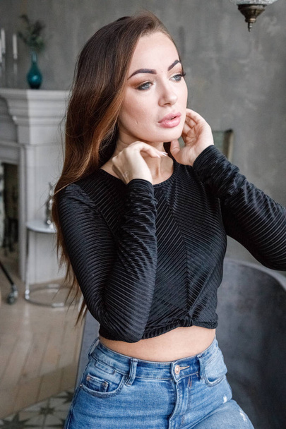 Portrait of beauty redhead woman in black blouse and blue jeans standing at luxury apartments interior   - Foto, imagen
