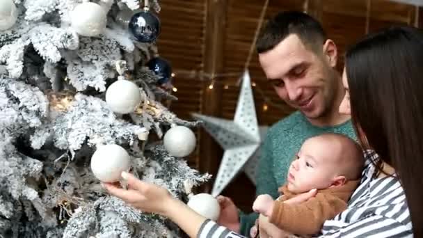 pais jovens mostram os brinquedos de Natal do bebê na árvore
 - Filmagem, Vídeo
