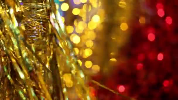 Celebração de Natal e Ano Novo. Decorações de grinalda de ouropel de Natal de ouro soprando na brisa. Luzes de Natal embaçadas piscando no fundo
. - Filmagem, Vídeo