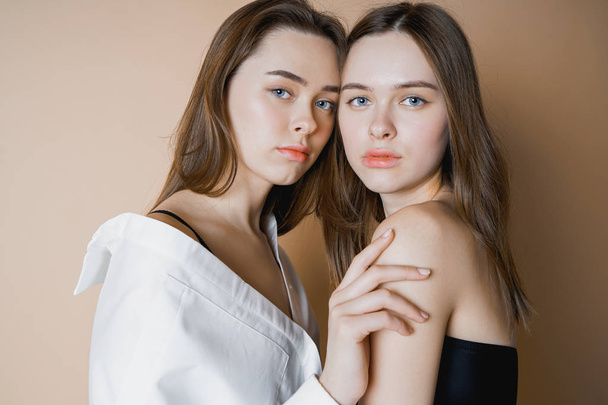 Moda modelos dos hermanas gemelas hermosas chicas desnudas mirando a la cámara aislada sobre fondo beige
                                - Foto, Imagen