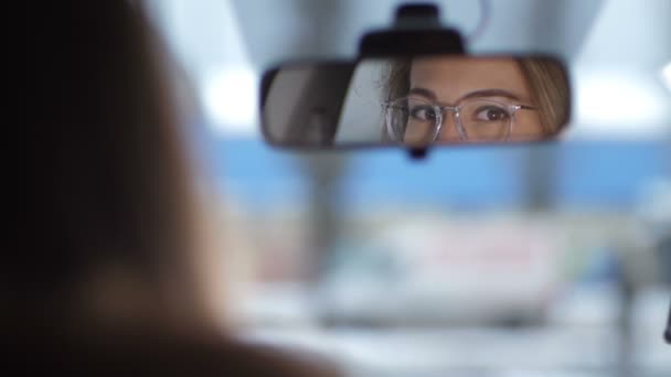 Σκοποβολή στο αυτοκίνητο, αντανακλάται στον καθρέφτη μπροστά. Όμορφα θηλυκά μάτια με γυαλιά κοιτάζουν γύρω από 4k αργή Mo - Πλάνα, βίντεο