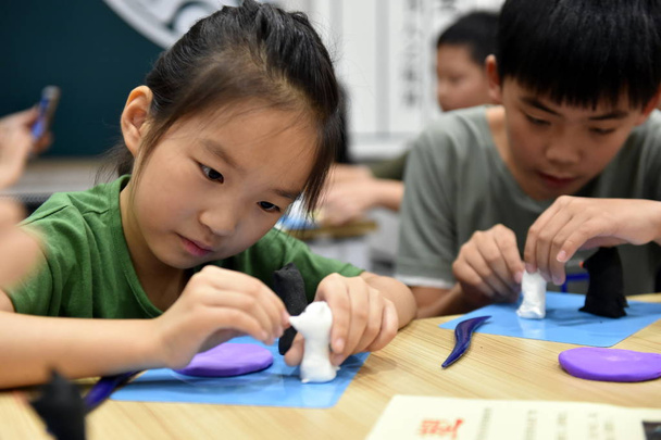 Primary school students make dough figurines during summer vacation in Hangzhou city, east China's Zhejiang province, 8 August 2018 - Photo, Image