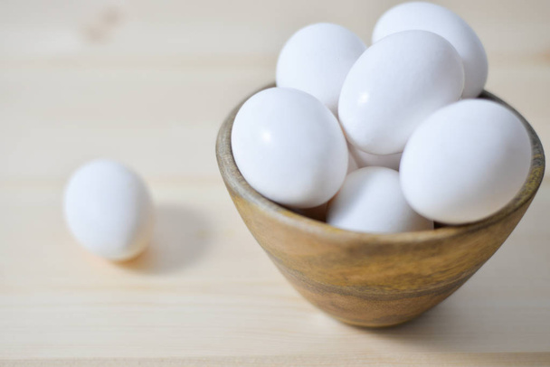 white eggs on wooden plate on wooden background , copy space  - Fotó, kép