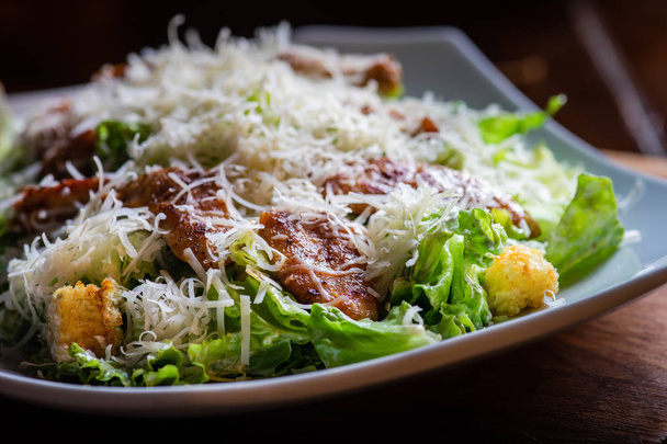 frischer Cesar-Salat mit Huhn, Croutons und Käse auf rustikalem Hintergrund - Foto, Bild