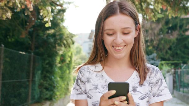 junge Frau benutzt Handy in der Stadt beim Gehen - Foto, Bild