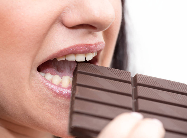 Close up of woman biting in a chocolate bar  - Фото, изображение