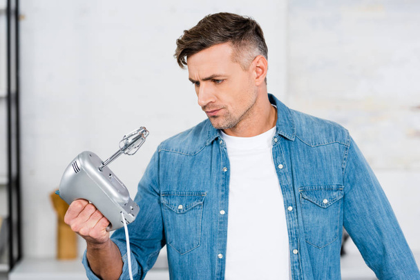 confused handsome man looking at kitchen mixer  - Photo, Image