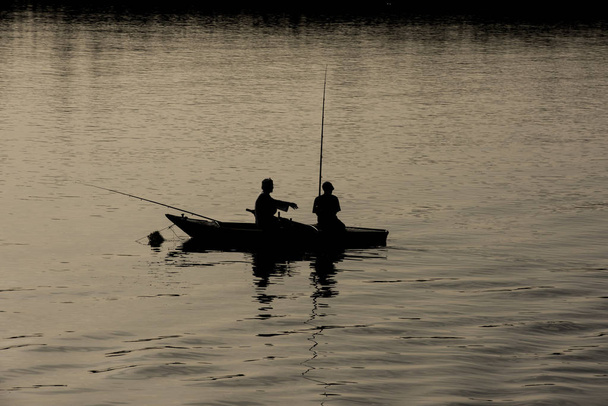Silhouette of traditional egyptian bedouin fisherman in rowing boat on river Nile at dusk sunset - Photo, Image