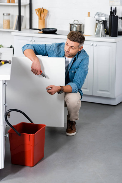 confused man repairing kitchen sink  - Фото, зображення
