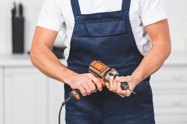 cropped view of repairman holding drill inhands  - Valokuva, kuva