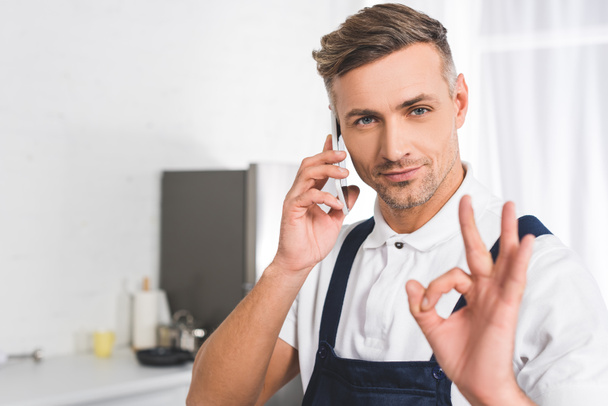 adult repairman talking on smartphone and showing ok sign - Photo, Image