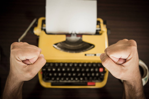 El escritor está delante de la máquina de escribir amarilla y finalmente está satisfecho con el texto que escribió
. - Foto, imagen