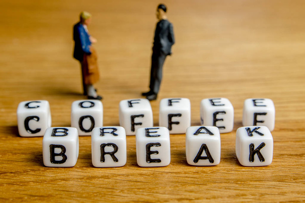 little miniature figurines with little dices forming specific word coffee break as a part of team meeting collection pictures dedicated to one part of its time table on wooden background - Foto, Imagem