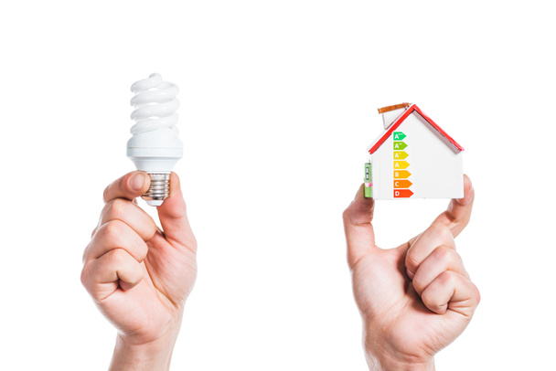 cropped view of male hands holding house model and fluorescent lamp in hands isolated on white, energy efficiency at home concept - Photo, Image