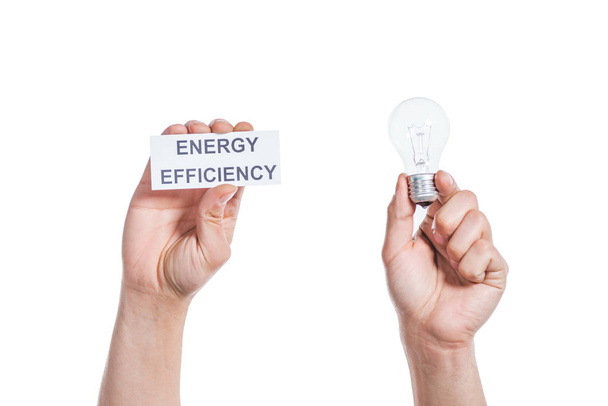 led ランプとエネルギー効率の概念を白で隔離の紙のカードを保持している男性の手のトリミング ビュー - 写真・画像