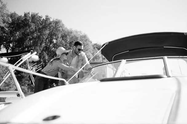 It's a black-and-white photo that shows a young beautiful couple looking at a speedboat that wants to rent. - Photo, Image