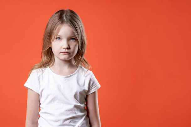 Portrait of a sad little girl over red background. - 写真・画像