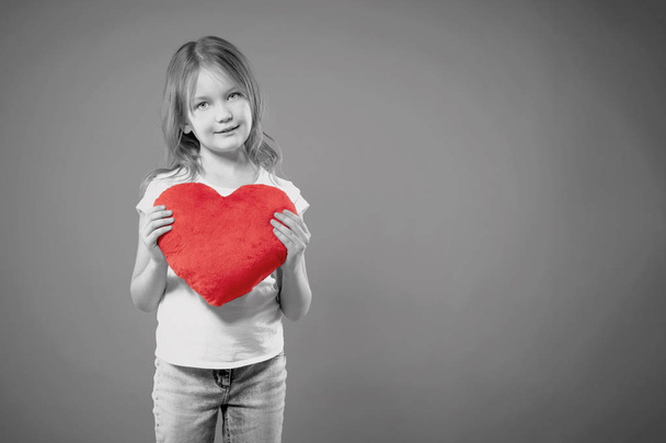 Cute little girl holding red heart over gray background. Love concept. Valentine's Day. Mothers Day. - Foto, immagini