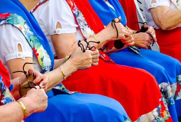 Κλείστε τα χέρια με καστανιέτες από γυναίκες κατά τη διάρκεια της παρουσίασης μιας ομάδας που καλλιεργεί την ισπανική παράδοση, μουσικά όργανα - Φωτογραφία, εικόνα