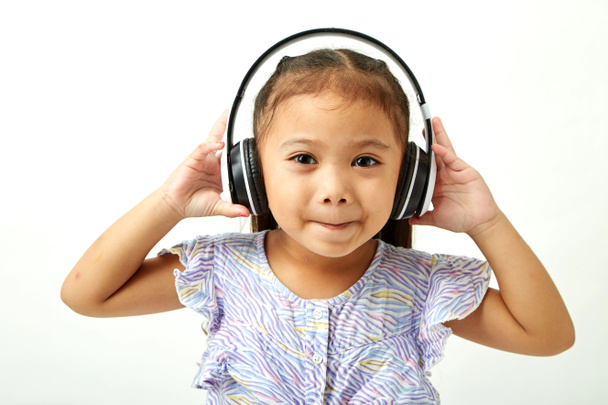 Asiatique Petite fille dans les écouteurs à l'écoute de la musique et en regardant la zone d'espace de copie
 - Photo, image