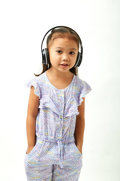 Asian Little girl in headphones listening to the music and looking to the copy space area - Фото, зображення