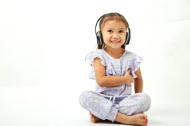 Asian Little girl in headphones listening to the music and looking to the copy space area - Foto, immagini