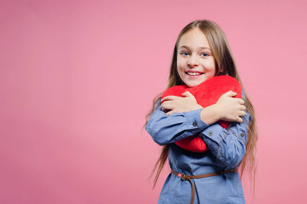 Love concept. Cute child girl holding red heart over pink background. Valentine's Day. Mothers Day. - Foto, imagen