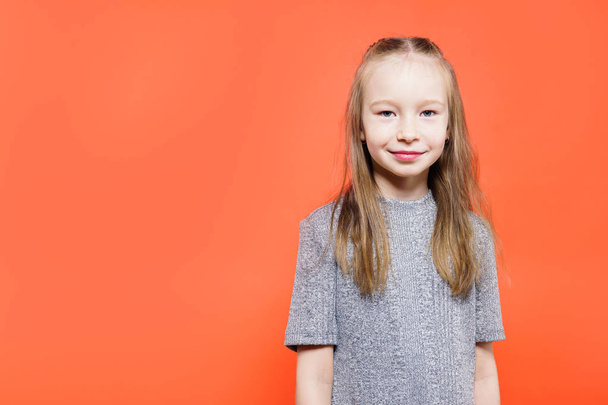 Portrait of a happy child girl over orange background. - Foto, Imagen