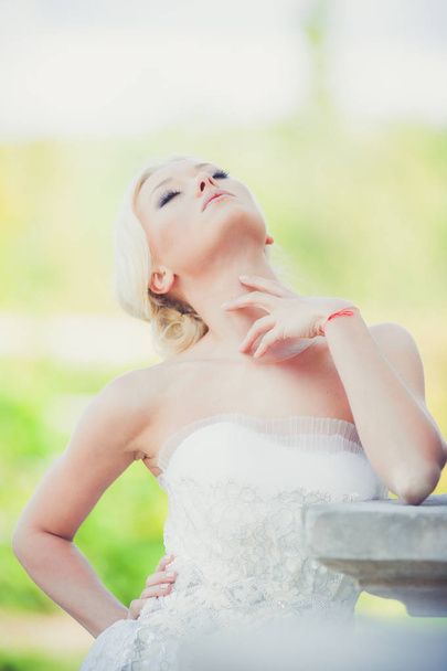 Sensual bride blonde in wedding dress near the palace before the wedding ceremony - Foto, afbeelding