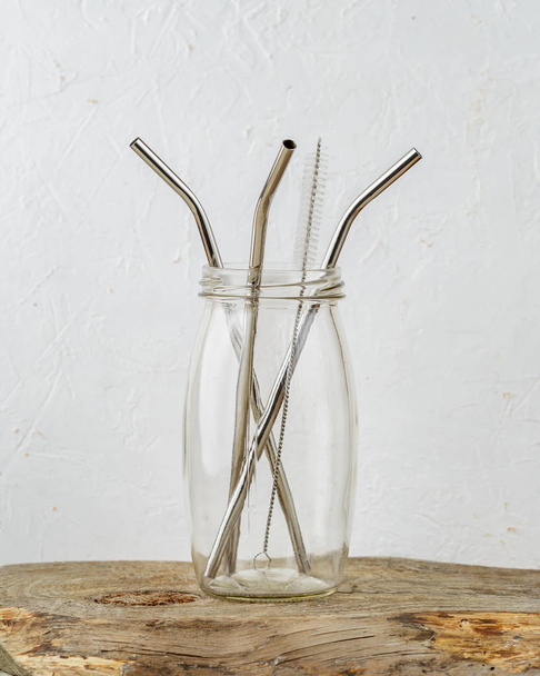 Три многоразовых соломинки для питья металла и щетка для чистки в банке на сером фоне. Нулевые отходы и минимализм
 - Фото, изображение