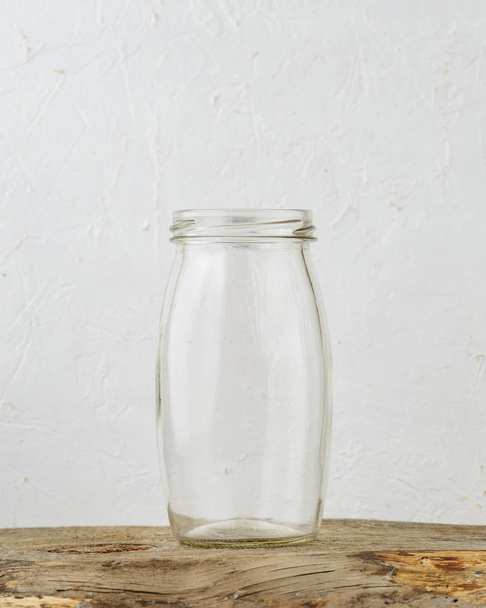 Empty glass jar on rustic wooden table over grey background - Photo, image