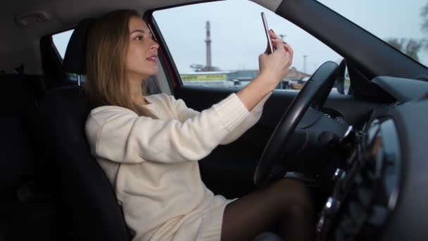 Mooi meisje in een korte jurk neemt foto's van zichzelf in de auto op verschillende manieren 4k Slow-Mo - Video