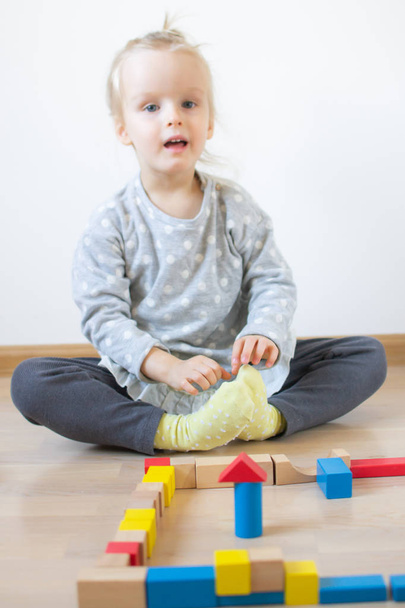 Niña caucásica jugando con cubos coloridos de madera en el hogar Educación temprana Preparándose para el desarrollo escolar
 - Foto, Imagen
