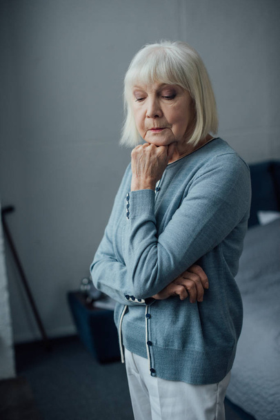 pensive senior woman in casual sweater propping chin with hand at home - Photo, Image